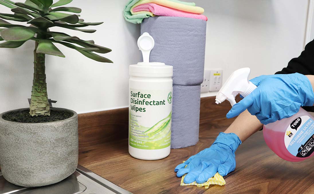 Female hand in gloves spraying a cleaning solution onto a counter