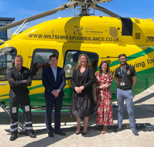 Five people standing in front of the Wiltshire Air Ambulance helicopter