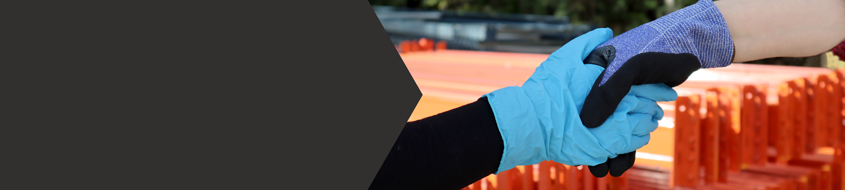 Two hands shaking on a construction site. One hand has a blue disposable glove, the other hand is wearing a thermal work glove.