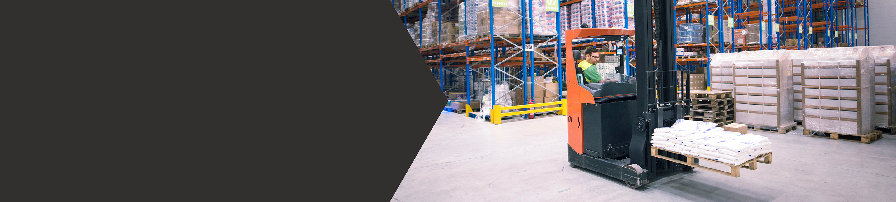 Man driving forklift with a pallet in a well-stocked warehouse